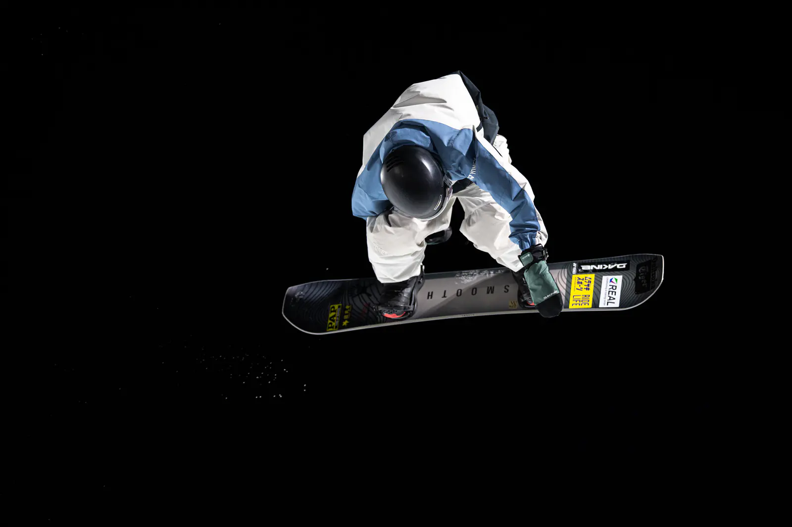 A snowboarder suspended in the air against a dark background